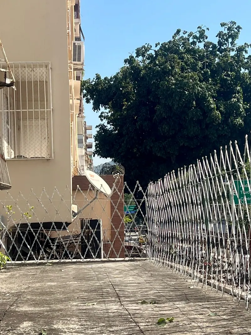 Rede laminada de losangos no alto do muro de uma esquina, com a rua atrás